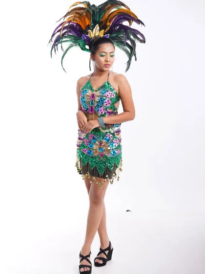 A vibrant and playful carnival-style costume, featuring a sequined green and blue dress with a dramatic feathered headdress.