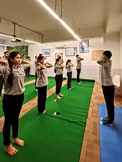 Employees participating in a standing warm-up exercise during our corporate yoga session. These simple movements help relieve shoulder and neck tension.