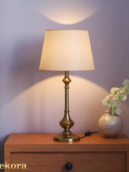 A sleek and classic table lamp with a brass base and a simple fabric shade. This timeless piece provides warm, diffused light, making it a perfect addition to a hotel room, reception area, or as a premium gift.