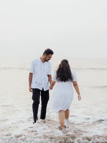 A candid shot of the couple walking into the waves, capturing a sense of adventure and shared journey.