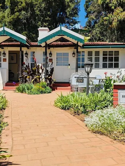 The entrance to one of the hotel's cottages, framed by lush gardens and a clean brick path, creating a picturesque scene.