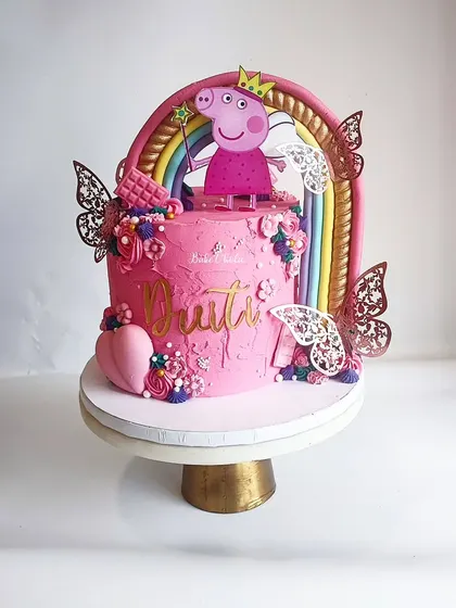 A different view of the Princess Peppa cake, highlighting the golden butterflies and textured pink ganache. It's all about adding those unique, magical touches.