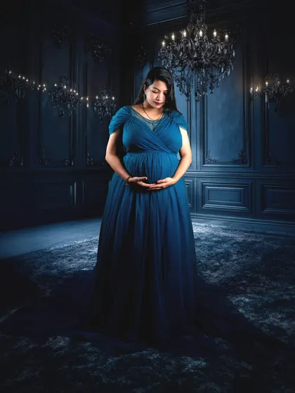 For those who love a touch of drama, our studio can be transformed into a moody and cinematic setting. This portrait uses dramatic lighting and a deep blue gown to create a truly artistic and memorable image of motherhood.
