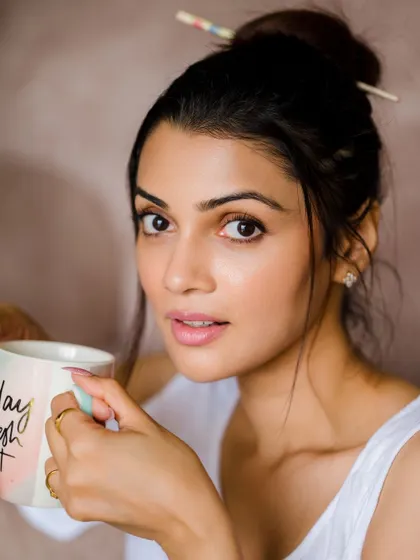 A beautiful, natural portrait capturing a quiet morning moment. The soft light and coffee cup prop make the scene feel authentic and relatable.
