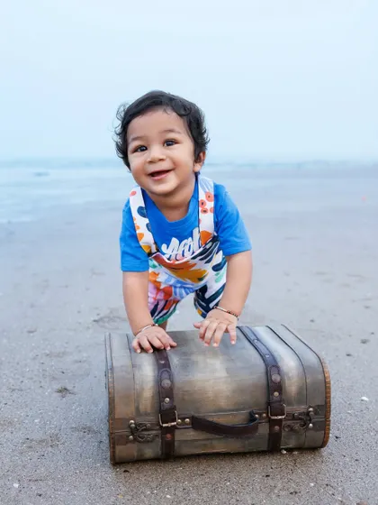 A little adventurer on the beach, ready to explore with his vintage suitcase prop during his first birthday session.