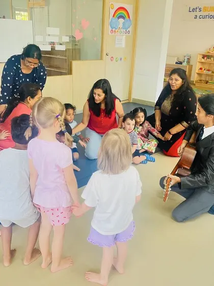 The children form a circle and hold hands during a music and movement activity. This encourages teamwork and coordination while they enjoy the rhythm and songs.