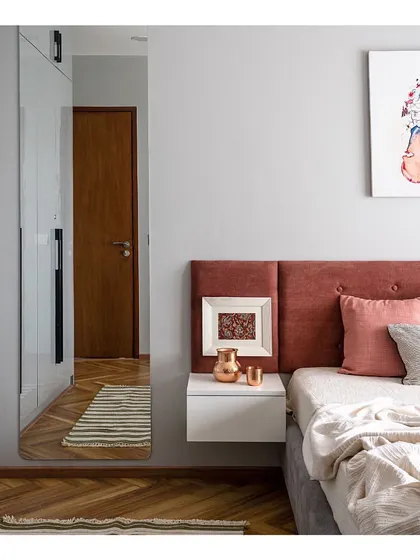 The guest bedroom is a welcoming space with a pop of personality. A rust-colored headboard and vibrant modern art piece contrast with the cool grey tones of the wardrobe and walls, creating a balanced and stylish room.