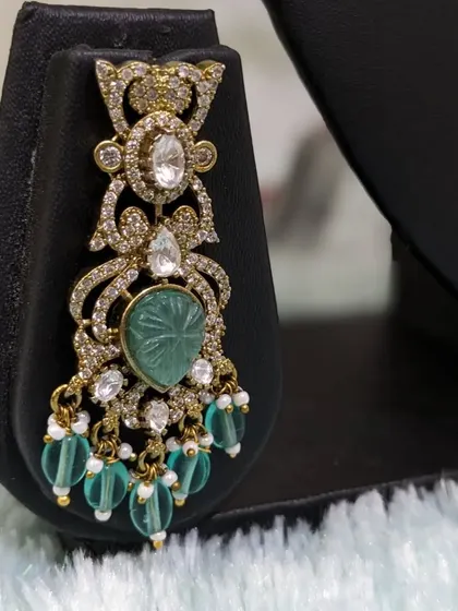 A close-up of the earring, highlighting the carved stone and moissanite sparkle.