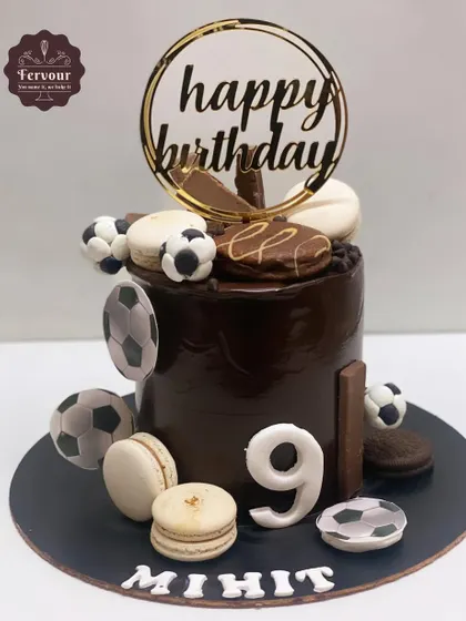 A football-themed chocolate truffle cake decorated with macarons and edible footballs. This is a more decadent and stylish take on a sports theme.