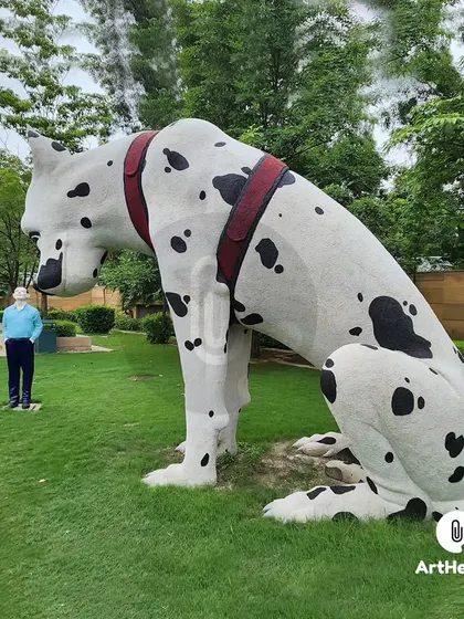 The giant Dalmatian sculpture seen from the side, giving a sense of its immense scale next to the human figure. This is a prime example of our custom outdoor art.