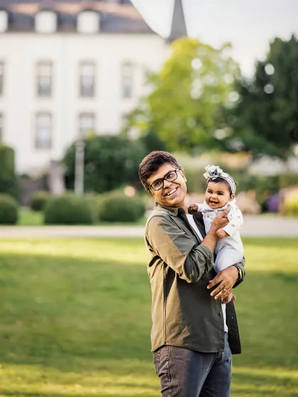 A father's joy holding his smiling baby girl in a park. These are the candid, happy memories that families will treasure for a lifetime.