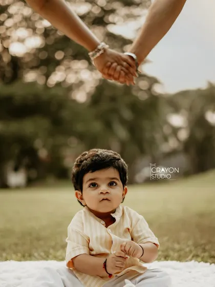 A creative shot focusing on the baby looking up, while his parents hold hands above him. It symbolizes the loving, protective world they have created for him.