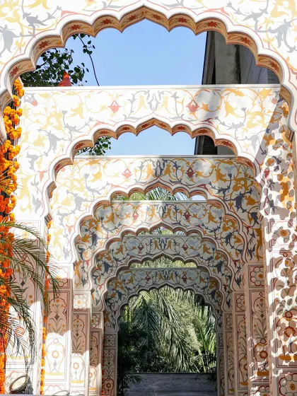 A closer look at the repeating arches of the Old Delhi entrance. The intricate, hand-painted patterns and garlands of marigolds create a sense of depth and architectural beauty.