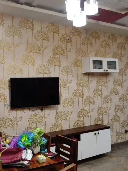 A living room with a repeating tree pattern wallpaper, creating a warm and inviting backdrop for the TV unit.