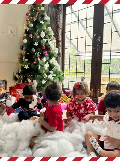 A group of toddlers sitting by the Christmas tree, taking in all the magical decorations.
