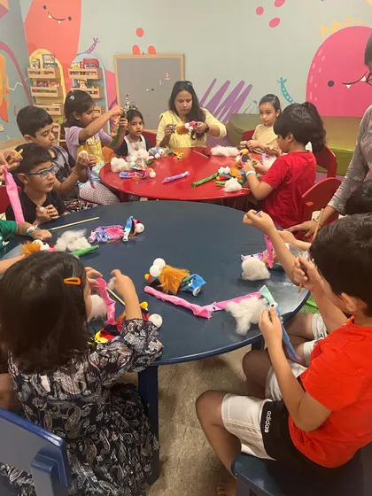 A busy table of little creators. Everyone is focused on making their own unique hand puppets, using different materials to express their artistic vision.