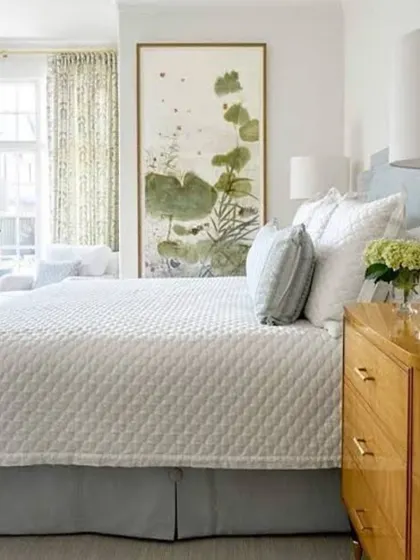 A clean and refreshing bedroom look. The walls are painted in a crisp off-white, allowing the natural wood tones and green artwork to become the room's focal points.