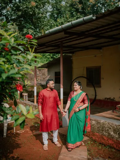 A couple holding hands and walking through the garden of a village home, creating a natural and candid pre-wedding photo.