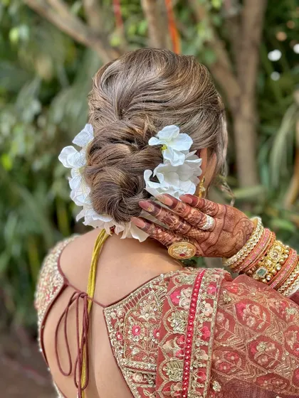 The hairstyle is a crucial part of the bridal look. This textured bun with fresh white flowers is a classic choice that adds a touch of romance.