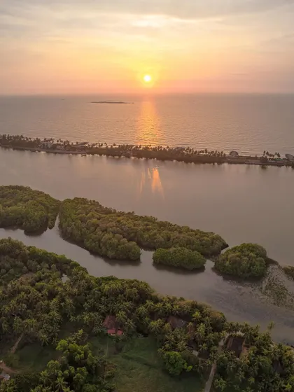 The stunning coastline of beautiful Tulunadu at sunset. This drone shot captures the unique geography where the river meets the sea, creating a beautiful natural barrier.