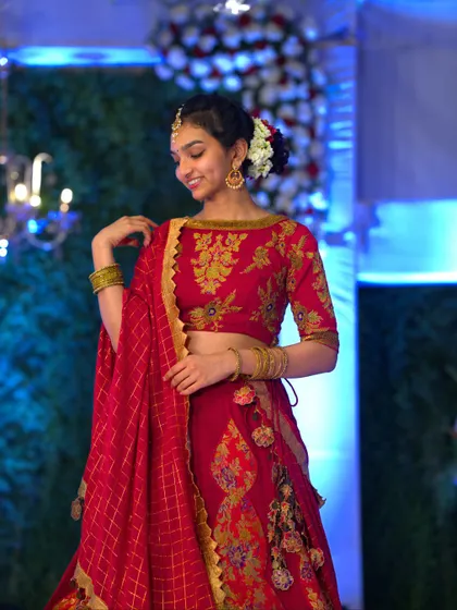 The joy of a bride is my greatest inspiration. Here, my client smiles, showcasing the custom-designed boat neck blouse with intricate gold embroidery that perfectly complements her red lehenga.