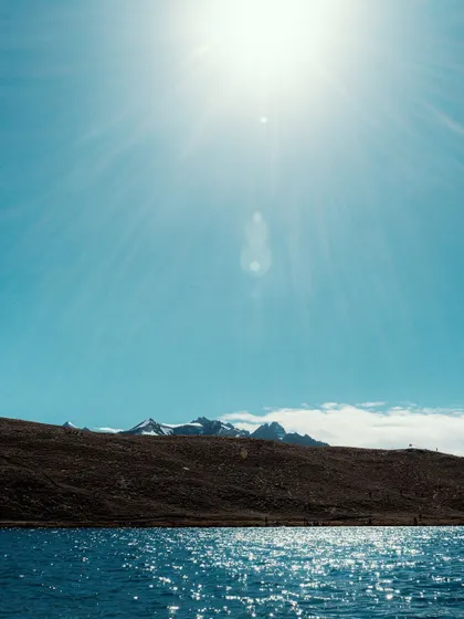The bright sun reflecting off a high-altitude lake. The intense blue of the water and sky is characteristic of the clear, thin air in the Himalayas.