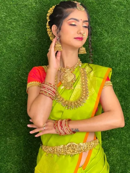 A full-length view of a South Indian bride, showcasing the complete look from the 'maang tikka' to the perfectly pleated saree.