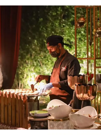 A close-up of our chef at a live tawa station, surrounded by elegant copper and brass serveware.