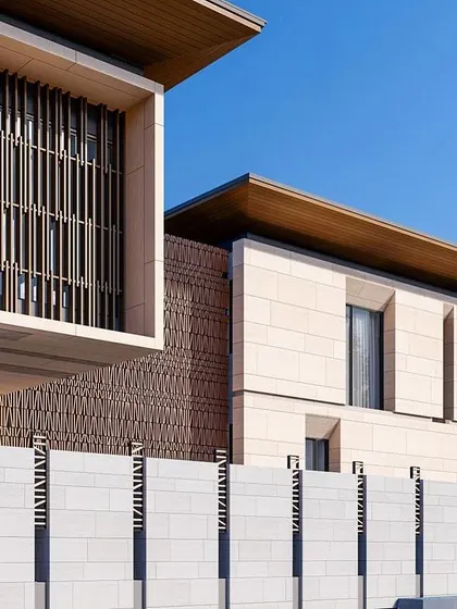 The boundary wall of this Goa residence continues the design language of the main house, with natural stone and vertical slats. This creates a cohesive and sophisticated street presence.