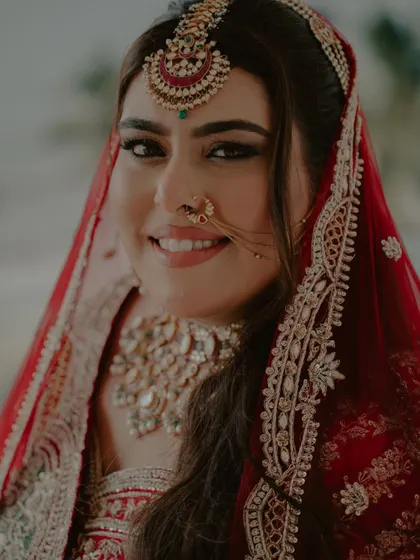 A close-up portrait of the bride, capturing her beautiful smile and the intricate details of her makeup and jewelry.