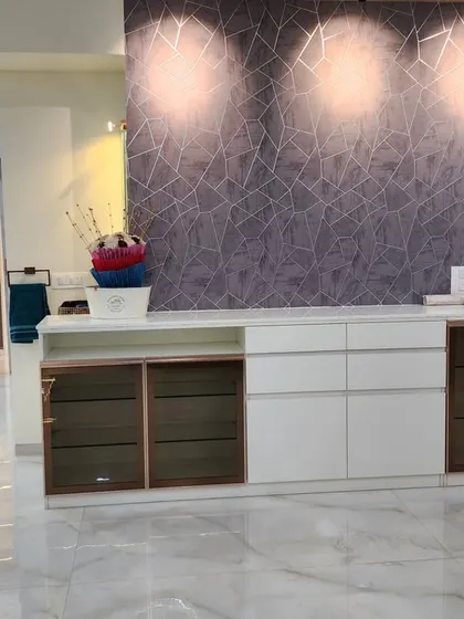 A view of the custom crockery and storage unit with a white countertop, smoked glass cabinet doors, and a textured wallpaper accent.