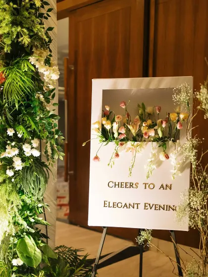 A unique 3D welcome sign with fresh flowers emerging from the center. This piece, reading "Cheers to an Elegant Evening," greeted guests at a joint 50th and 80th birthday party.
