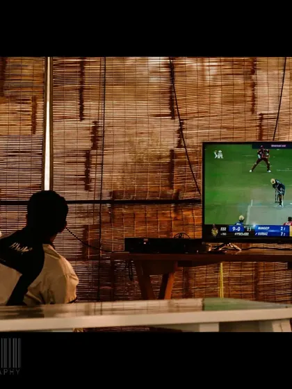 A person watching an IPL cricket match on TV in a rustic cafe. This image captures the passion for cricket that unites so many people across the country.