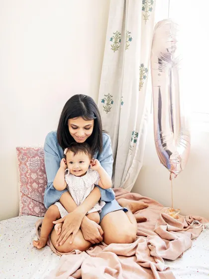 A mother and daughter sit on the bed with a birthday balloon nearby. This candid black and white photo captures a simple, happy memory at home.