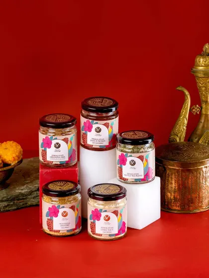 A product lineup of Valley Culture's healthy salt and spice mixes, styled against a rich red backdrop. The arrangement on white blocks gives the products height and presence, showcasing them as a premium offering.