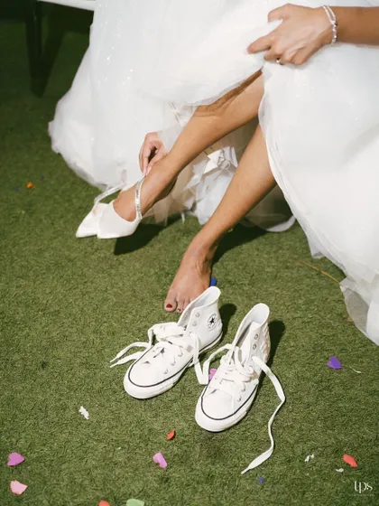 A fun and relatable moment as the bride swaps her heels for comfortable sneakers. This shot captures the real, unscripted parts of the wedding day.