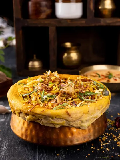 A traditional "dum" biryani, with the dough seal still on, creating anticipation for the aromatic dish inside.