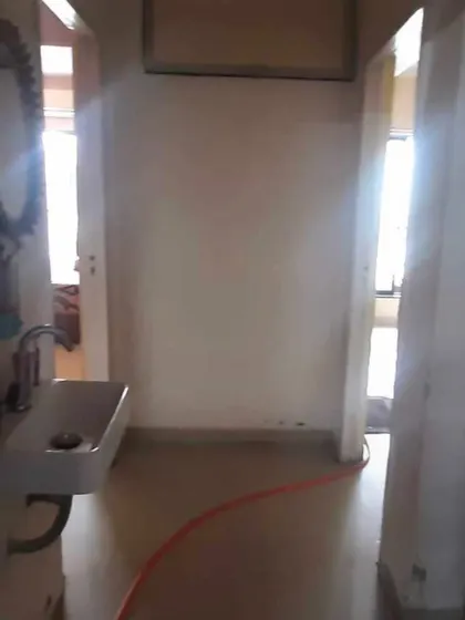 This passage before the makeover has exposed finishes and a small washbasin, showing the starting point for our entryway transformation.