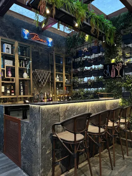 A full view of the stunning terrace bar we designed. The combination of a living wall, hanging plants, neon signs, and industrial-chic furniture creates a sophisticated and vibrant commercial-grade space.