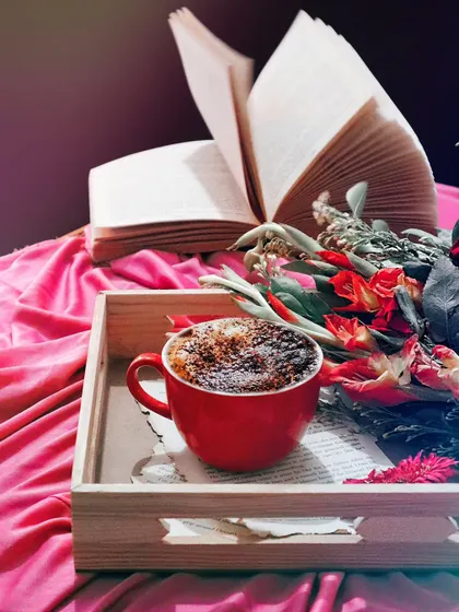 A different version of the coffee and book flatlay, with a more dramatic, vintage filter. The lighting and composition evoke a sense of timelessness and romance.