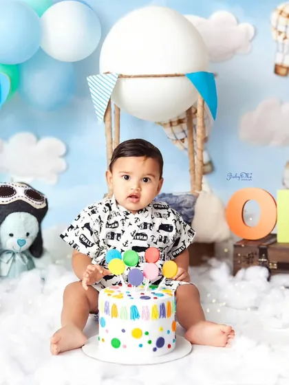 On cloud nine with his colourful birthday cake! This hot air balloon themed cakesmash is full of whimsy and fun. The bright polka dots on the cake add another pop of joy to the celebration.