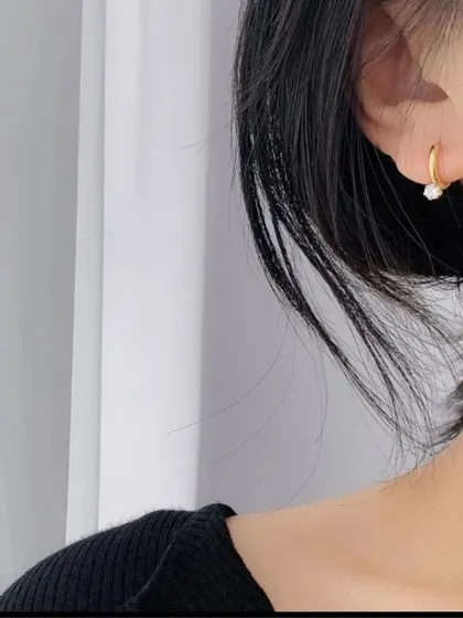 A model showcasing the small gold-toned hoop earring with a single crystal charm. It's a minimalist design that is perfect for everyday elegance.