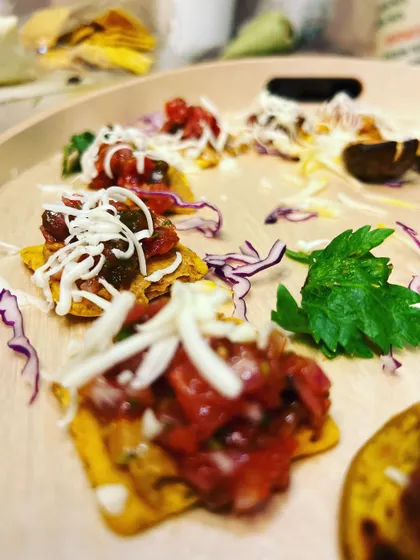 A close-up of our star-shaped nachos topped with fresh salsa and shredded cheese. We elevate simple concepts into gourmet experiences with high-quality ingredients and careful presentation.