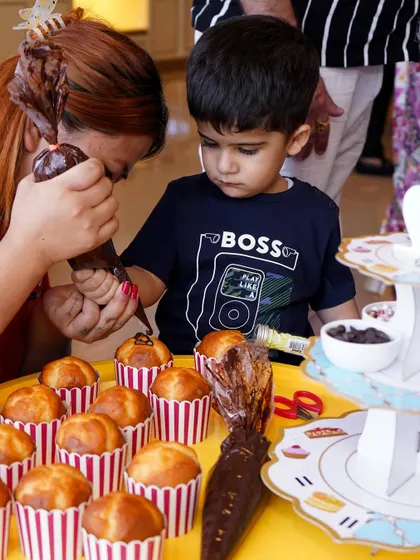A young boy gets help decorating cupcakes, a fun and delicious party activity.