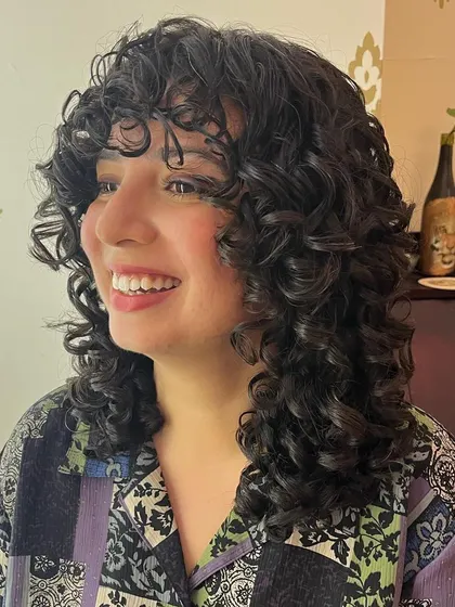 A happy client enjoying her new, easy-to-style curly shag.