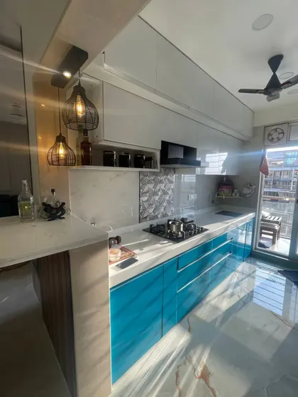 The morning sun brightens up this beautiful kitchen. This shot captures the breakfast bar area with its pendant lights, the sleek blue cabinets, and the view from the balcony, showing a space that's a joy to be in.