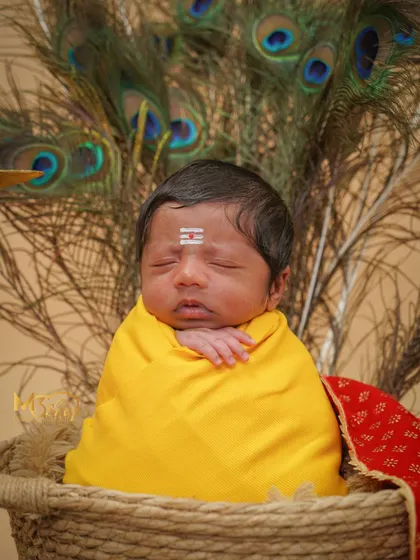A simpler version of the theme, focusing on the baby's peaceful face against the peacock feather backdrop. The beauty is in the simplicity.