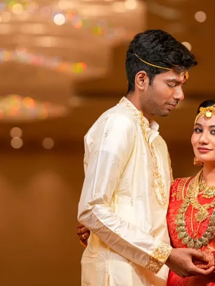A classic portrait of the couple, showcasing the bride's stunning red saree and temple jewelry.