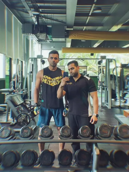 A mirror selfie of a member with his personal trainer, reflecting the supportive and collaborative environment we cultivate. Our trainers are your partners in achieving your goals.