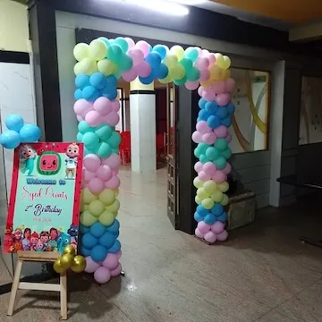 A colorful balloon archway for a Cocomelon themed second birthday party. A welcome sign on an easel greets guests at the entrance.